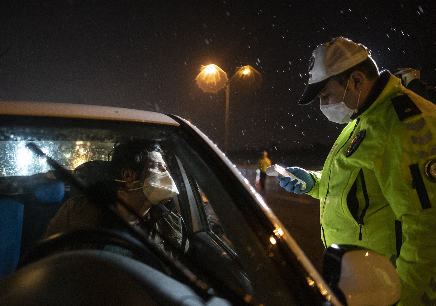 A Turkish police officer checks the temperature of a driver at an exit of Istanbul, Turkey, 28 March 2020. According to reports Turkey has banned intercity bus travel walks and fishing along the seashore and beaches, as well as jogging in forests and parks on weekends amid coronavirus outbreak for thirty metropolitan cities