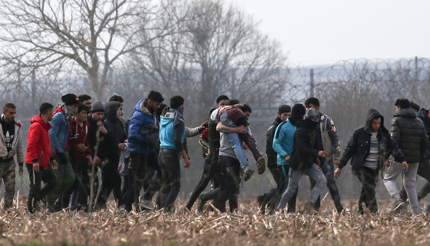 Migrants carry a wounded and run from tear gas thrown by Greek policemen as they wait for attempting to pass the closed-off Turkish-Greek border and try to enter Europe, Edirne, Turkey, 04 March 2020. 