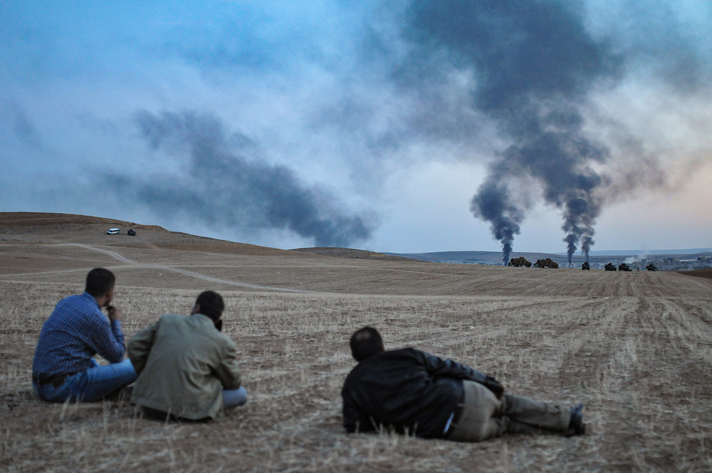 People look at smoke rising from an explosion following a US-led coalition airstrike on Kobane, Syria, as seen from the Turkish side of the border, near Suruc district, Sanliurfa, Turkey, 26 October