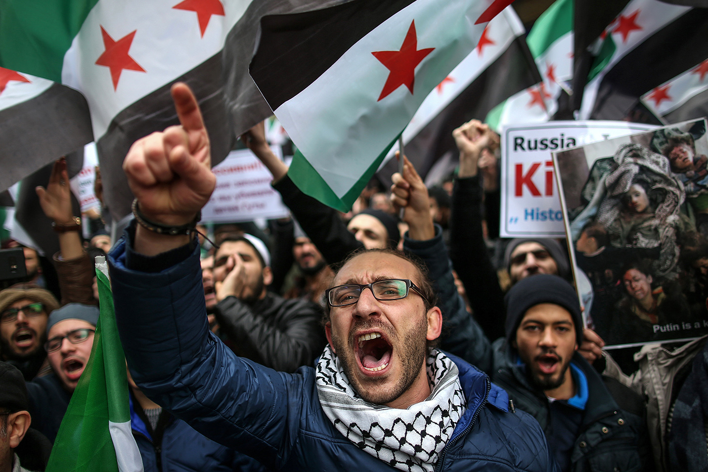  Syrian refugees hold placards and the Syrian National Coalition flag while shouting anti-Russia slogans for the country