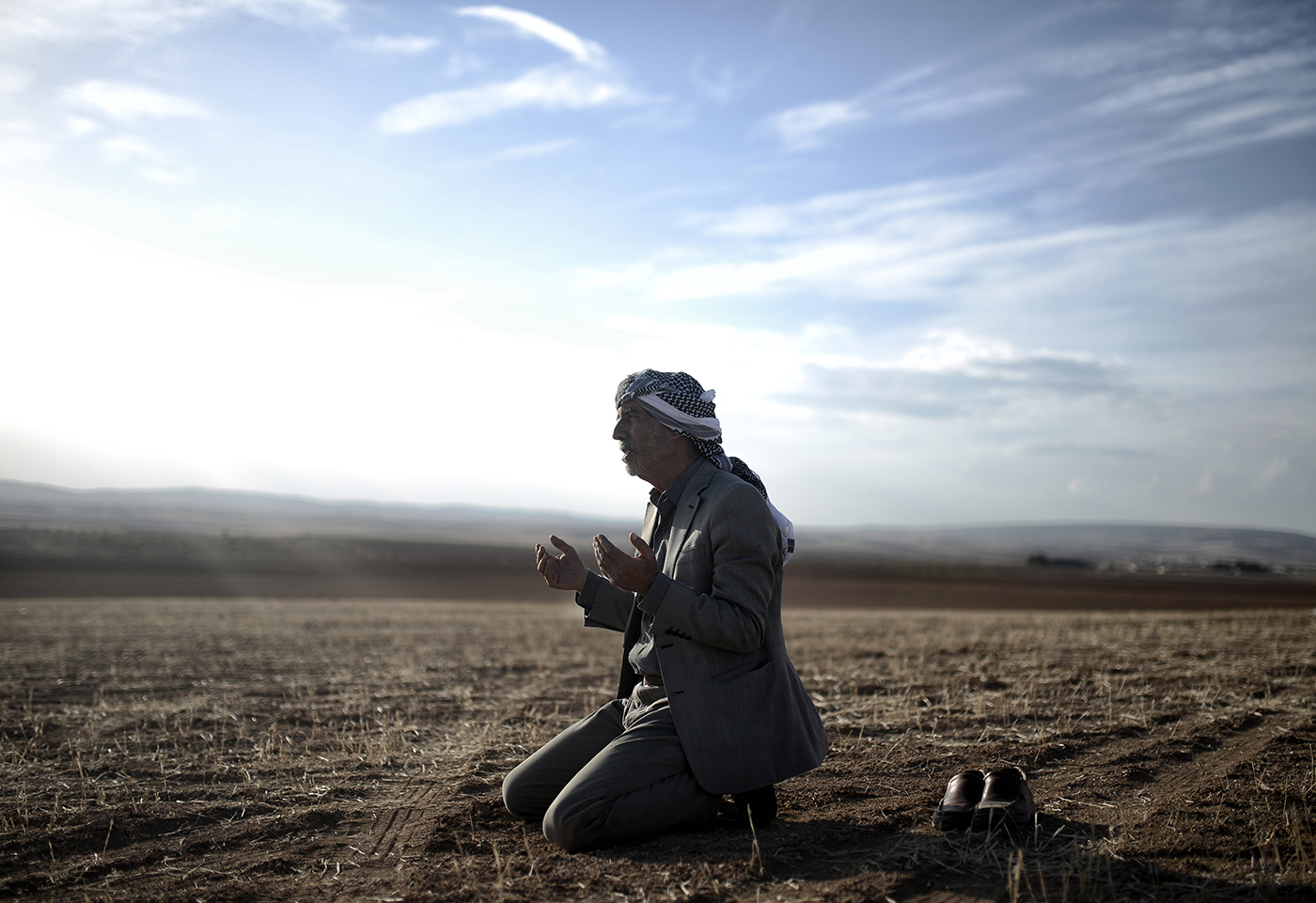 A man pray for Syrian people at the Kobane as he watch xplosion after an apparent US-led coalition airstrike on Kobane, Syria, as seen from the Turkish side of the border, near Suruc district, Sanliurfa, Turkey, 26 October 2014.