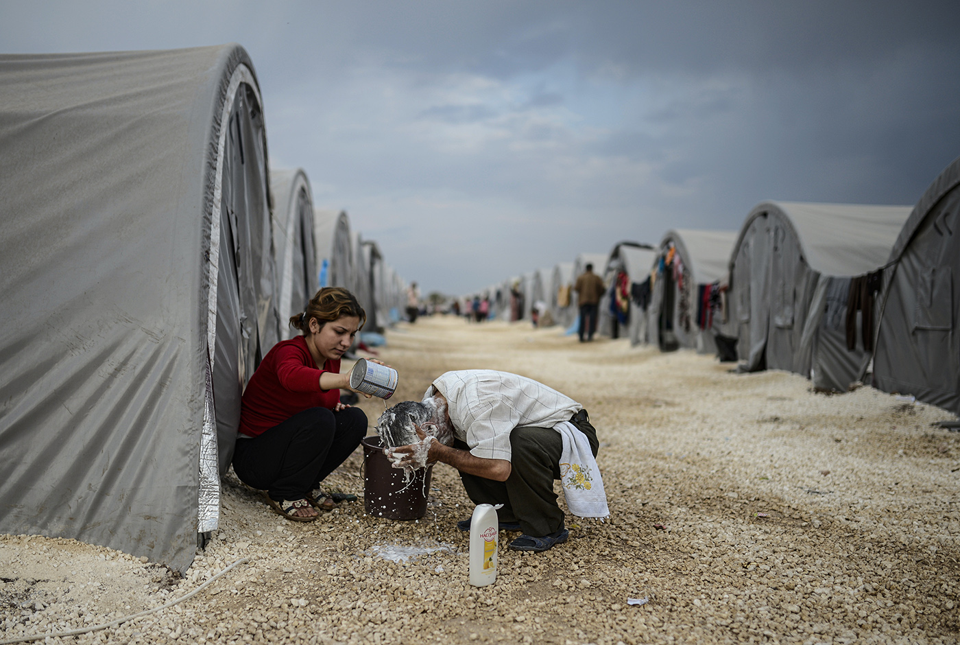 A Syrian refugee man washes his hair in front of their tent at the refugee camp in Sanliurfa, Turkey, 28 October 2014.