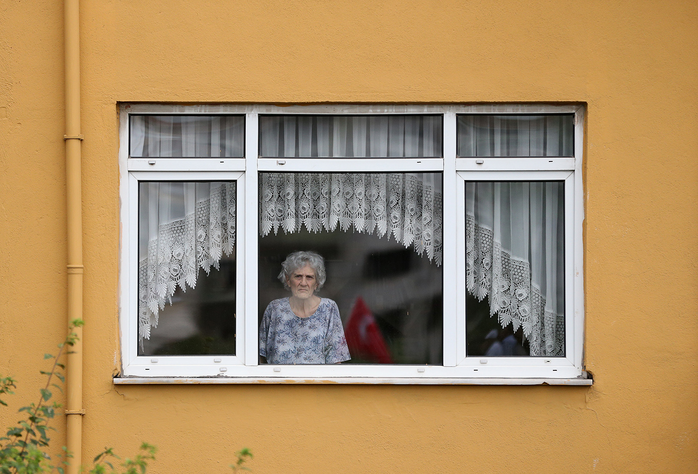 A woman looks from a window of her house as supporters of Turkey