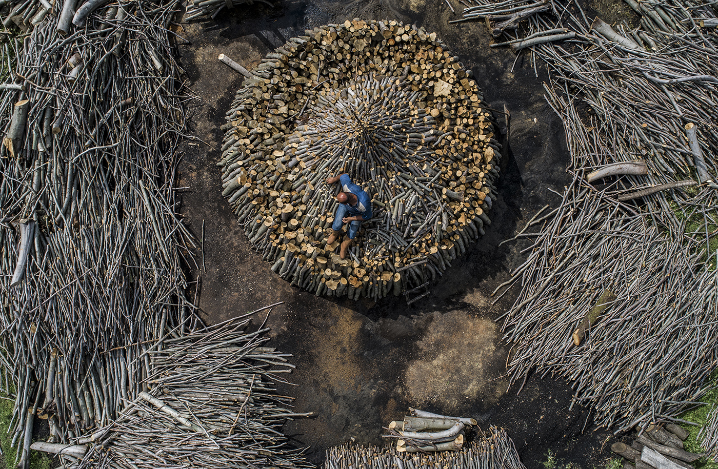An aerial photo taken by a drone shows, a charcoal worker during preparations for the handcrafted charcoal in Istanbul, Turkey, 24 May 2019 (Issued on 26 May 2019) According to reports, 250,000 tonnes of charcoal are consumed every year in Turkey. Each year in the northern forests of Istanbul, traditional charcoal production starts in the summer The peasants living in the region cut their oak trees and systematically line them up as a circle, Then they covered it with soil and set on fire for a week, it is expected to cool down in two days.