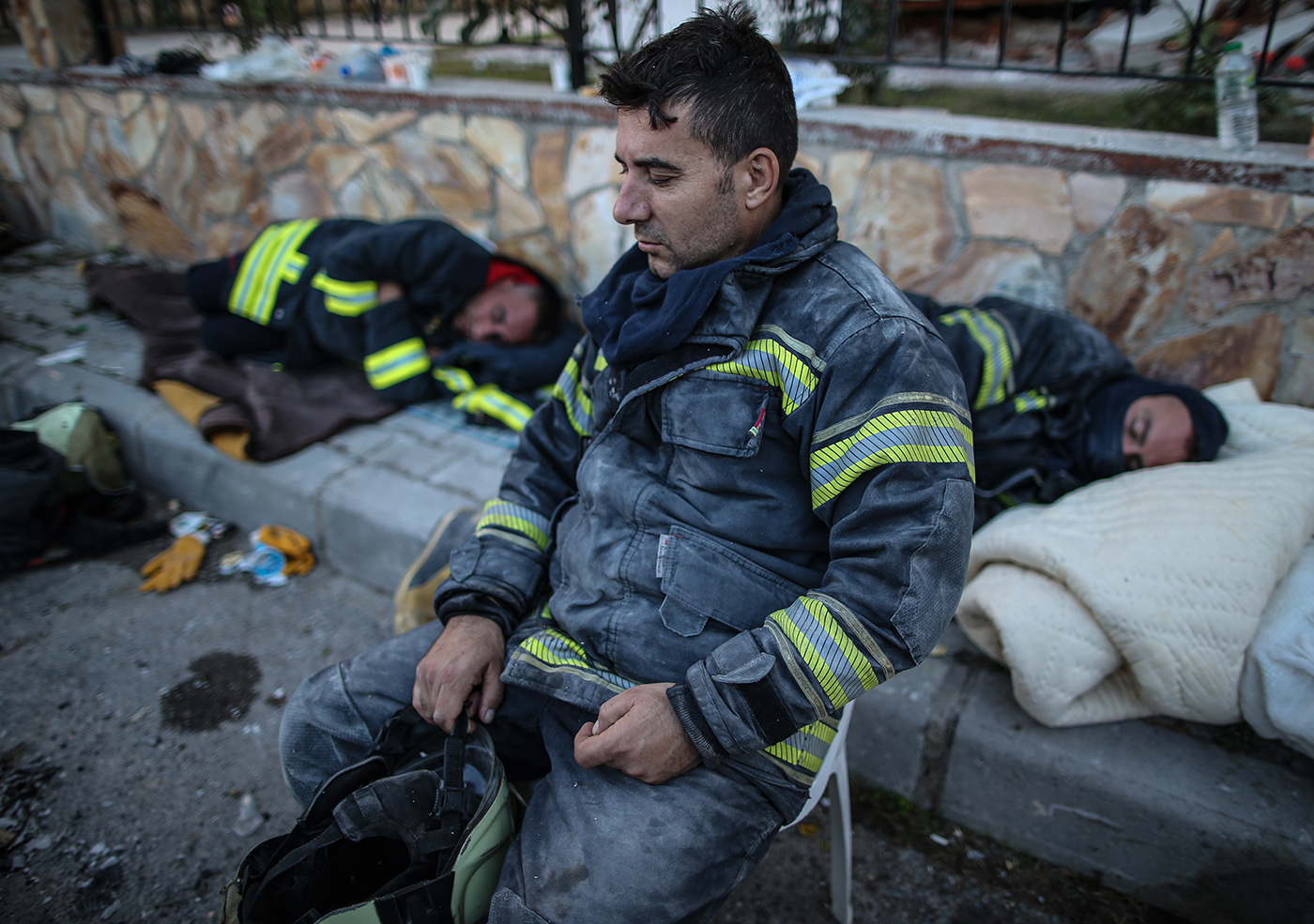 Rescue workers rest around a fire after a 7.0 magnitude earthquake in the Aegean Sea, at Bayrakli district in Izmir, Turkey, 01 November 2020. According to Turkish media reports, at least forty nine people died while more than eight  hundreds were injured and dozens of buildings were destroyed in the earthquake.