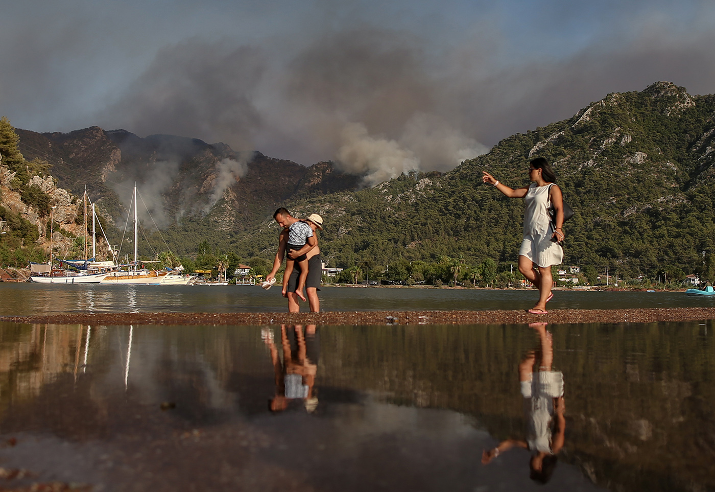 People enjoy in the sea backdopped by the  wildfire burning in Marmaris district of Mugla, Turkey, 31 July 2021. According to a statement by the Turkish government