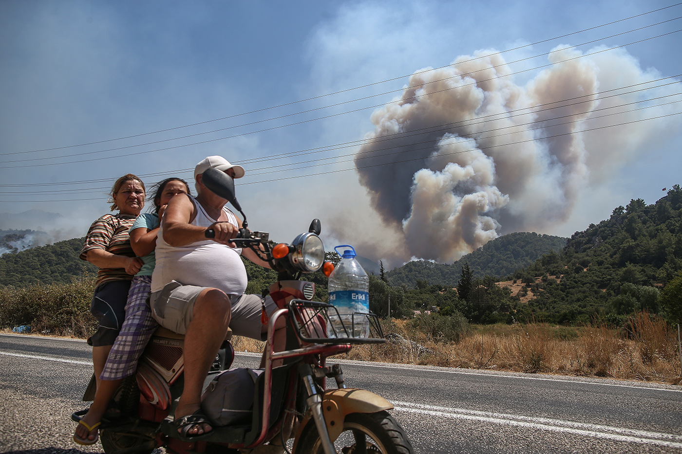 Poeple pass by motorcycle in front of a wildfires at the rural of Marmaris district of Mugla, Turkey, 01 August 2021. Turkish Health minister Fahrettin Koca confirmed that 6 people have lost their lives due to the wildfires raging in Turkey’s Mediterranean towns.