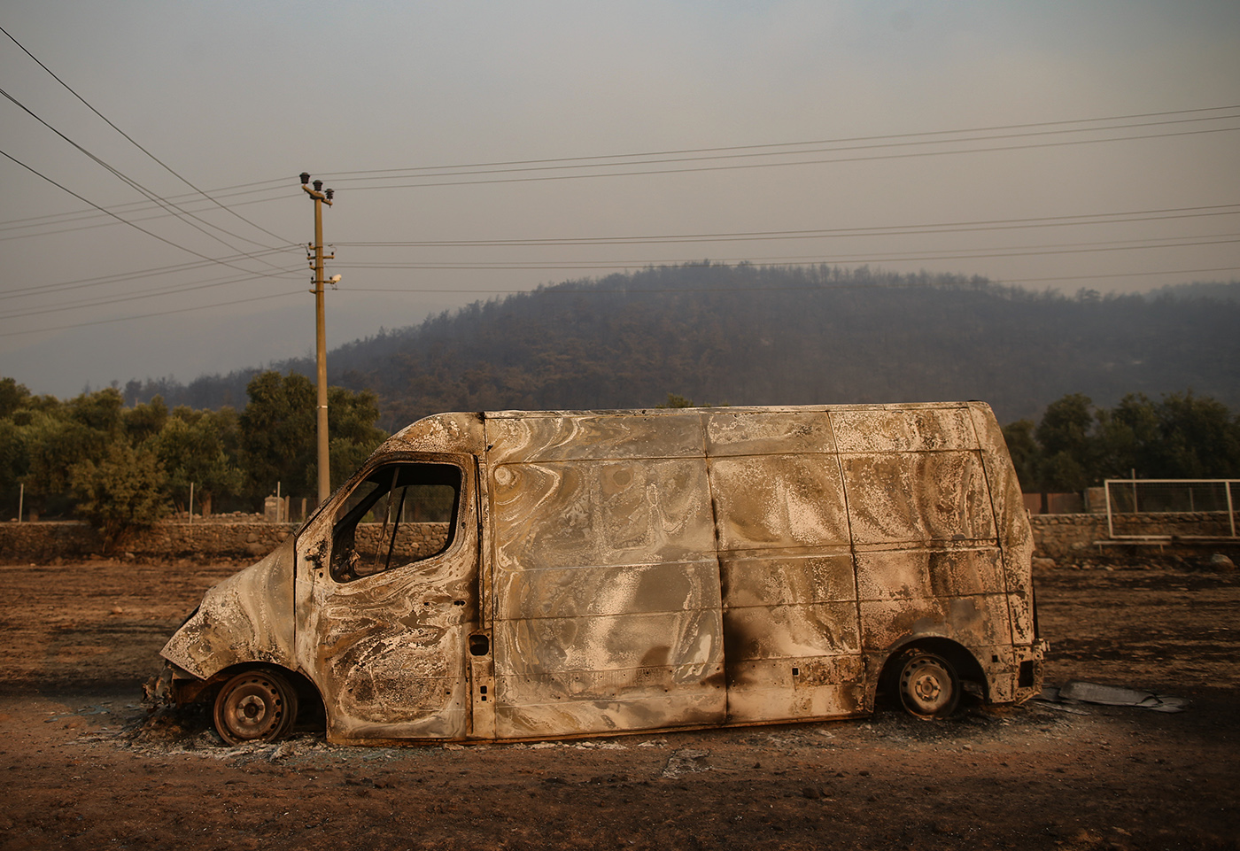 A burned car after a wildfire swept through at the Cokertme village of Milas district of Mugla, Turkey, 02 August 2021. Turkish Health minister Fahrettin Koca confirmed that eight people have lost their lives due to the wildfires raging in Turkey’s Mediterranean towns.