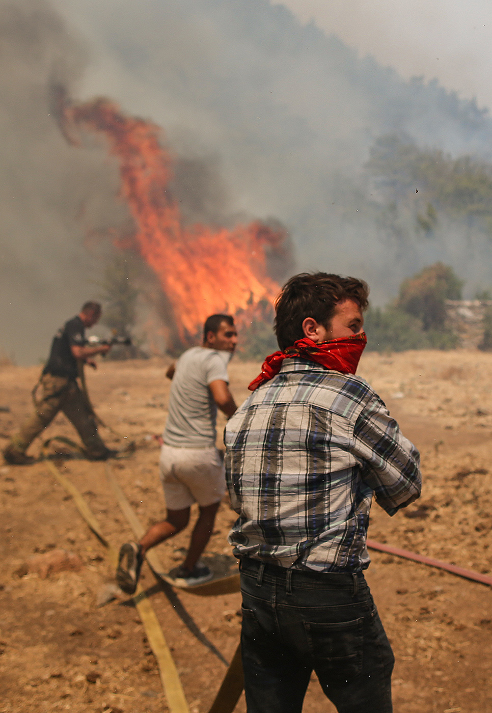 People fight with the wildfire burning at the Cokertme village of Milas district of Mugla, Turkey, 02 August 2021. Turkish Health minister Fahrettin Koca confirmed that eight people have lost their lives due to the wildfires raging in Turkey’s Mediterranean towns.