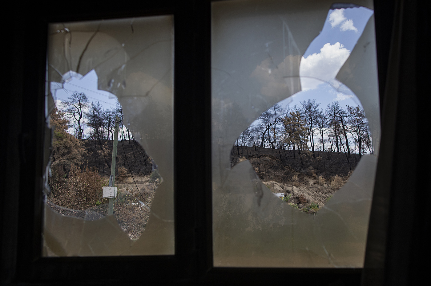 Burnt trees from a damged window of a burnt house after a wildfire at the Evrenseki village of the Manavgat district of Antalya, Turkey, 10 August 2021.