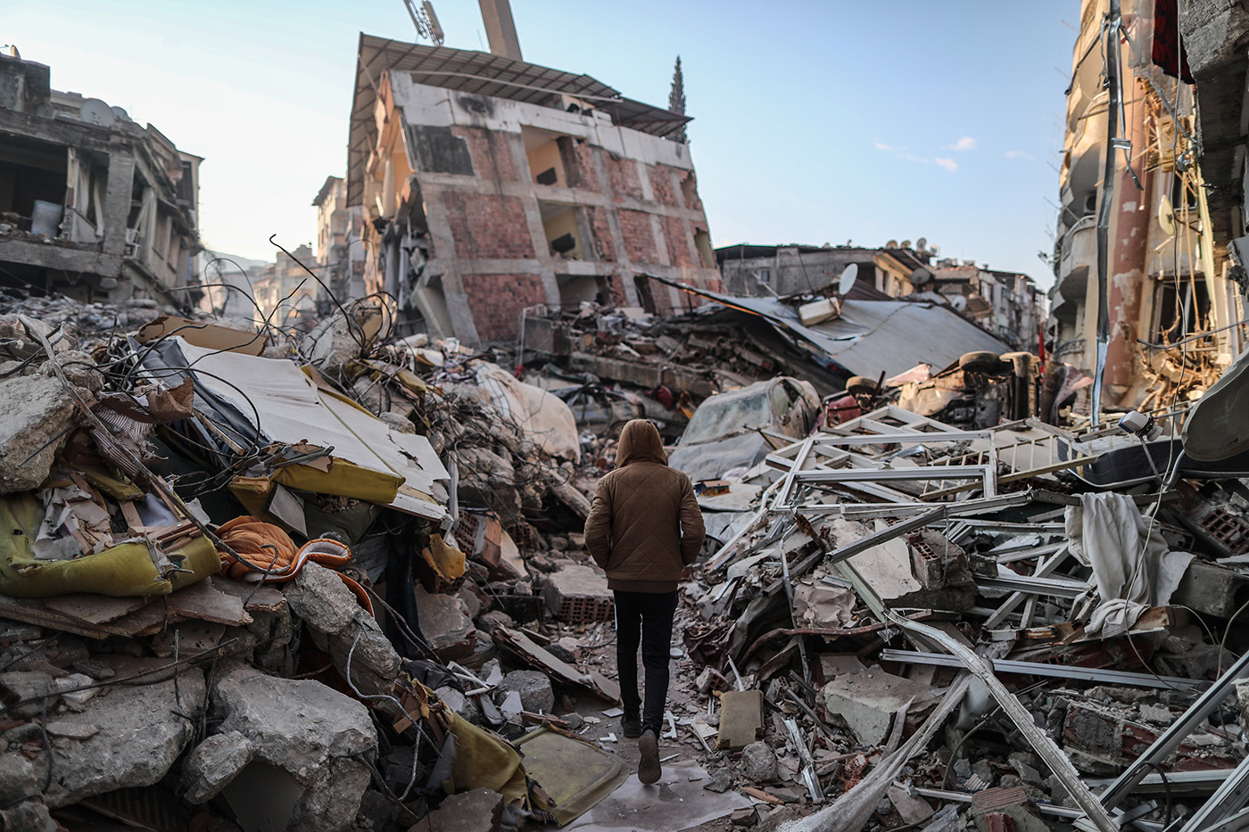  man walks next to collapsed buildings after a powerful earthquake in Hatay, Turkey, 11 February 2023. More than 24,000 people have died and thousands more are injured after two major earthquakes struck southern Turkey and northern Syria on 06 February. Authorities fear the death toll will keep climbing as rescuers look for survivors across the region.
